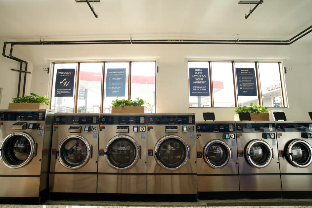 Row of large commercial washers below the front windows at The Laundry Hub SF
