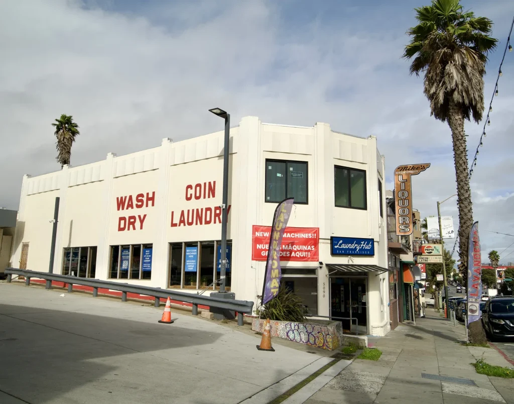 The Laundry Hub SF storefront on Mission Street with WASH DRY COIN LAUNDRY painted across the building