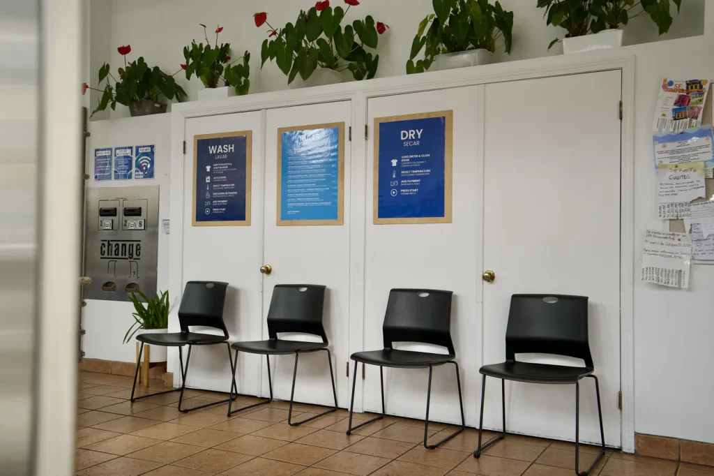 Seating below the bilingual WASH and DRY instruction boards at The Laundry Hub SF